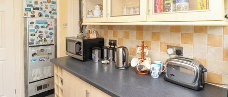 A kitchen with a refrigerator, microwave, toaster, and various kitchen items on the counter.