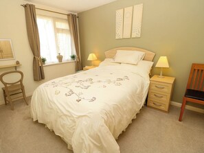 A bedroom with a bed, two bedside tables with lamps, a chair, a window with curtains, and wall art. - 14 Shorwell (Southampton)