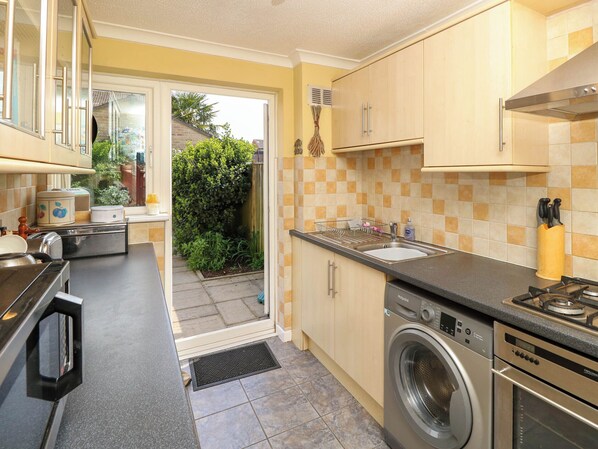 A compact kitchen with a washing machine, a sink, and a stove.