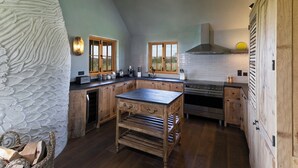 A kitchen with a central island, wooden cabinets, a stove, and a large window. - Wilderness Reserve - Hayjack (Saxmundham)