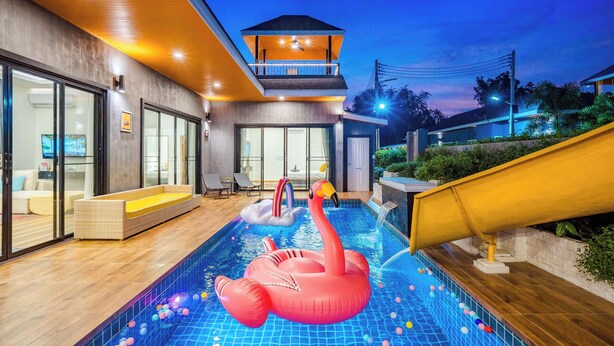 Ein modernes Haus mit Swimmingpool, aufblasbarem Flamingo und Rutsche.
