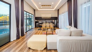 Ein modernes Wohnzimmer mit einer Couch, einem Hocker und einem Essbereich mit Stühlen.
