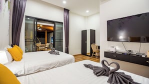 Ein Hotelzimmer mit zwei Betten, einem Fernseher, einem Schreibtisch und Blick ins Freie.