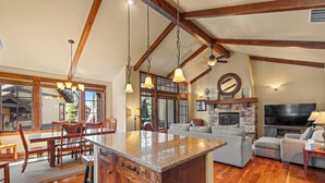 A spacious living area with a large wooden dining table, a built-in kitchen island, and a cozy seating arrangement. - Lady Luck by the Beach - Downtown Greystone unit with air conditioning (McCall)