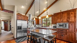 A spacious kitchen with wooden cabinets, stainless steel appliances, and a large island with stools. - Lady Luck by the Beach - Downtown Greystone unit with air conditioning (McCall)