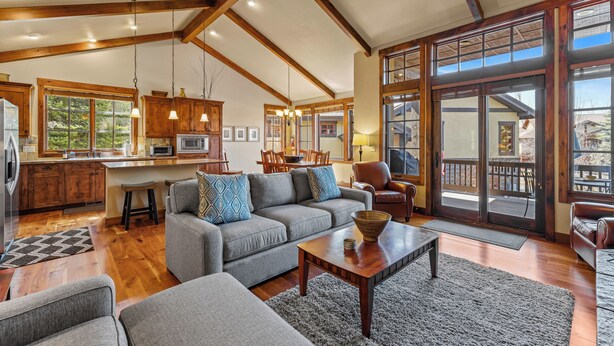 A spacious living area with a gray sofa, wooden coffee table, and a large window offering a view of the outdoors. - Lady Luck by the Beach - Downtown Greystone unit with air conditioning (McCall)