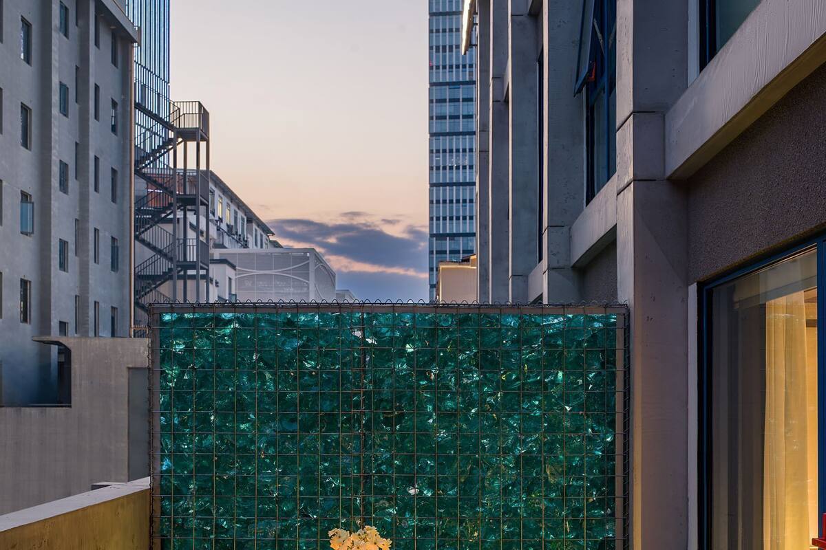 A balcony with a table set for two, surrounded by chairs, with a view of tall buildings in the background.