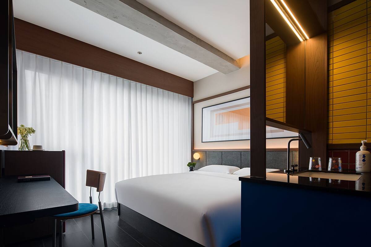 A modern hotel room with a large bed, a desk, and a bathroom.