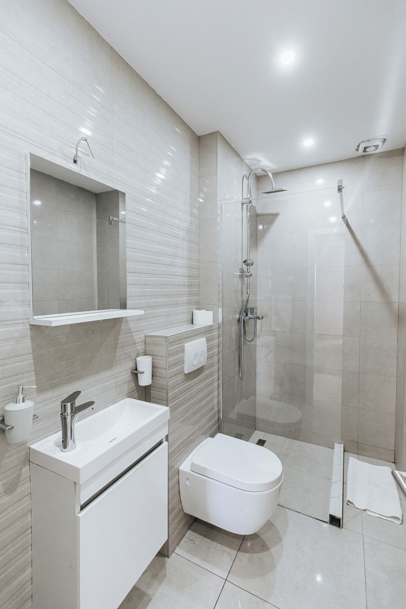 Un baño moderno con lavamanos, inodoro y ducha blancos.