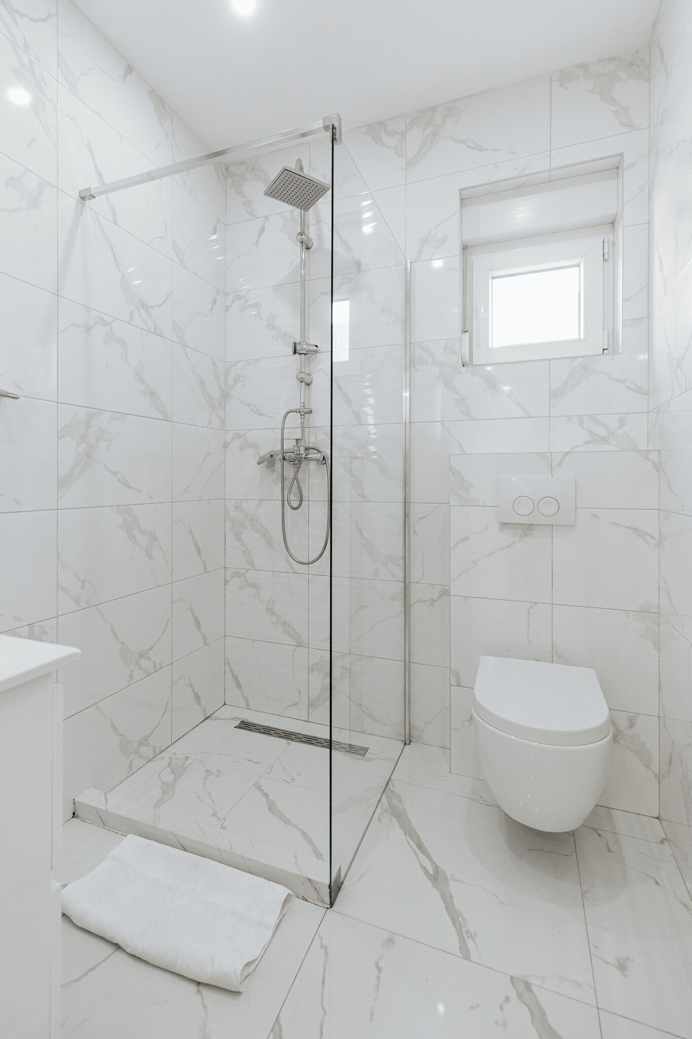 A modern bathroom with a glass-enclosed shower, a toilet, and a sink.