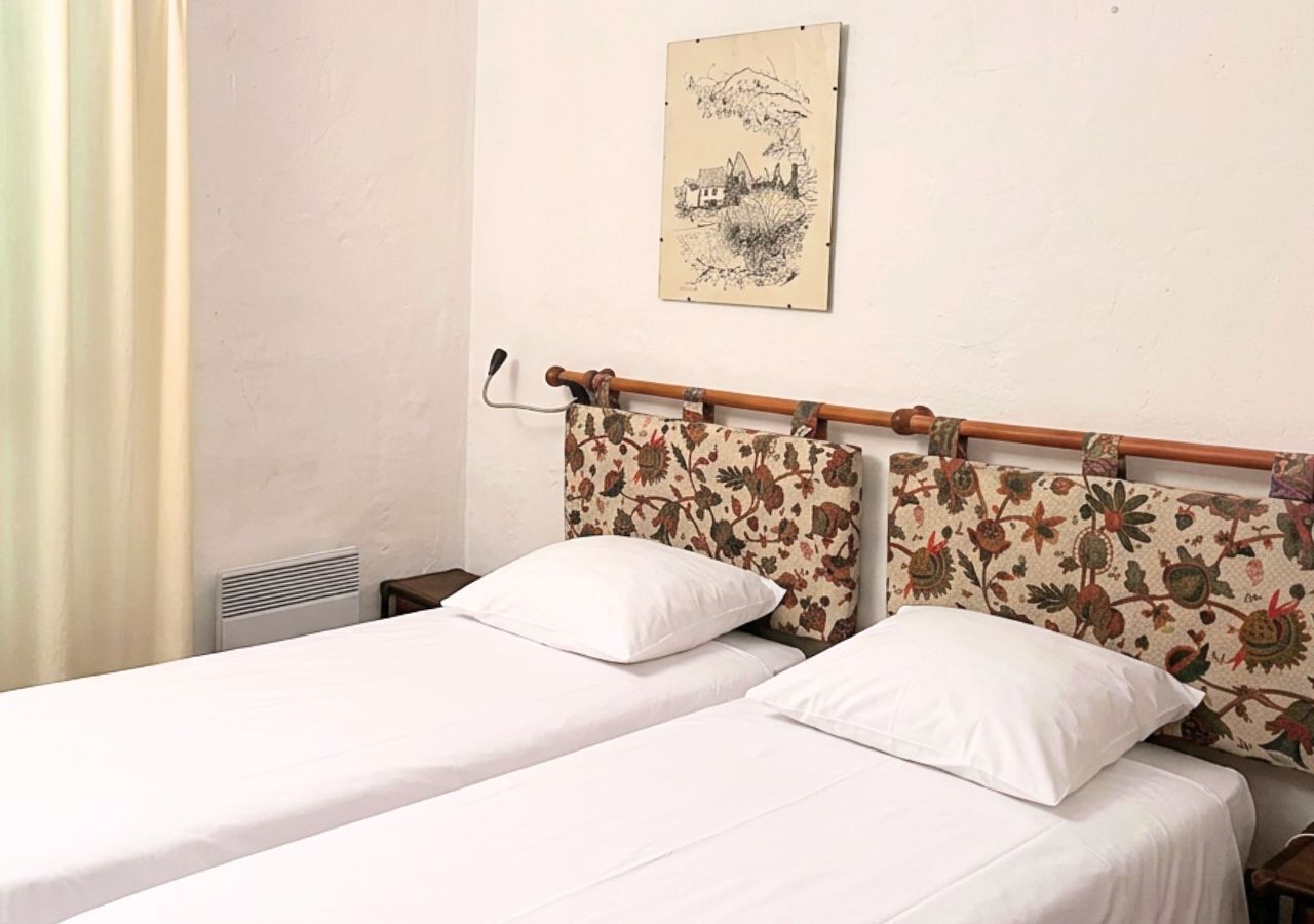 A double bed with floral headboard, white bedding, and a wall-mounted artwork.