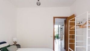 Une chambre à coucher comprenant un lit, une table de chevet, une lampe et une armoire avec un espace pour suspendre les vêtements.