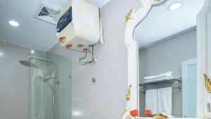 Een badkamer met een toilet, een douche, een wastafel met spiegel en een toiletrolhouder.