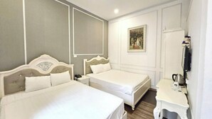 Een hotelkamer met twee bedden, een nachtkastje met een lamp, een schilderij aan de muur en een kledingkast.