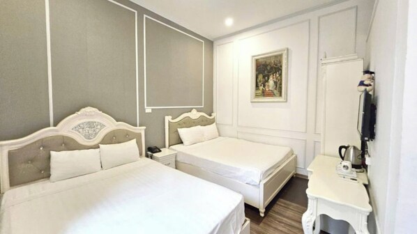 A hotel room with two beds, a bedside table with a lamp, a painting on the wall, and a wardrobe. - Hanoi 0riental Hostel (Hanoi)