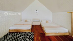 Ein kleines, gemütliches Schlafzimmer im Dachgeschoss mit zwei Einzelbetten, Holzboden und Wand mit Ziegelmuster.
