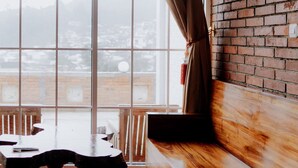 Ein Zimmer mit großem Fenster, einer Ziegelwand und einem Holztisch.