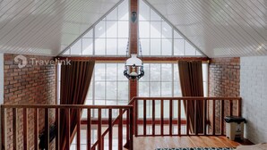 Ein geräumiger Raum mit hoher Decke, großen Fenstern und einer hängenden Leuchte.