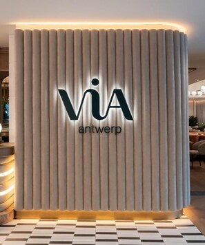 A reception area with a vertical panel design and illuminated 'via antwerp' signage. - Via Antwerp (Antwerp)
