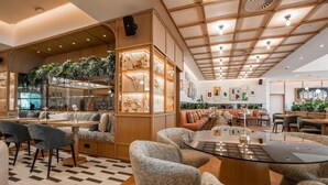 Un interno moderno con pavimento a scacchi, zone relax e un bar con piante.