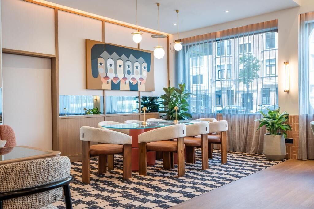 Un comedor moderno con una mesa de vidrio, sillas acolchadas y un suelo a cuadros.