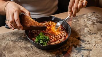 Eine Person schöpft Essen aus einer Bratpfanne auf einen Teller.