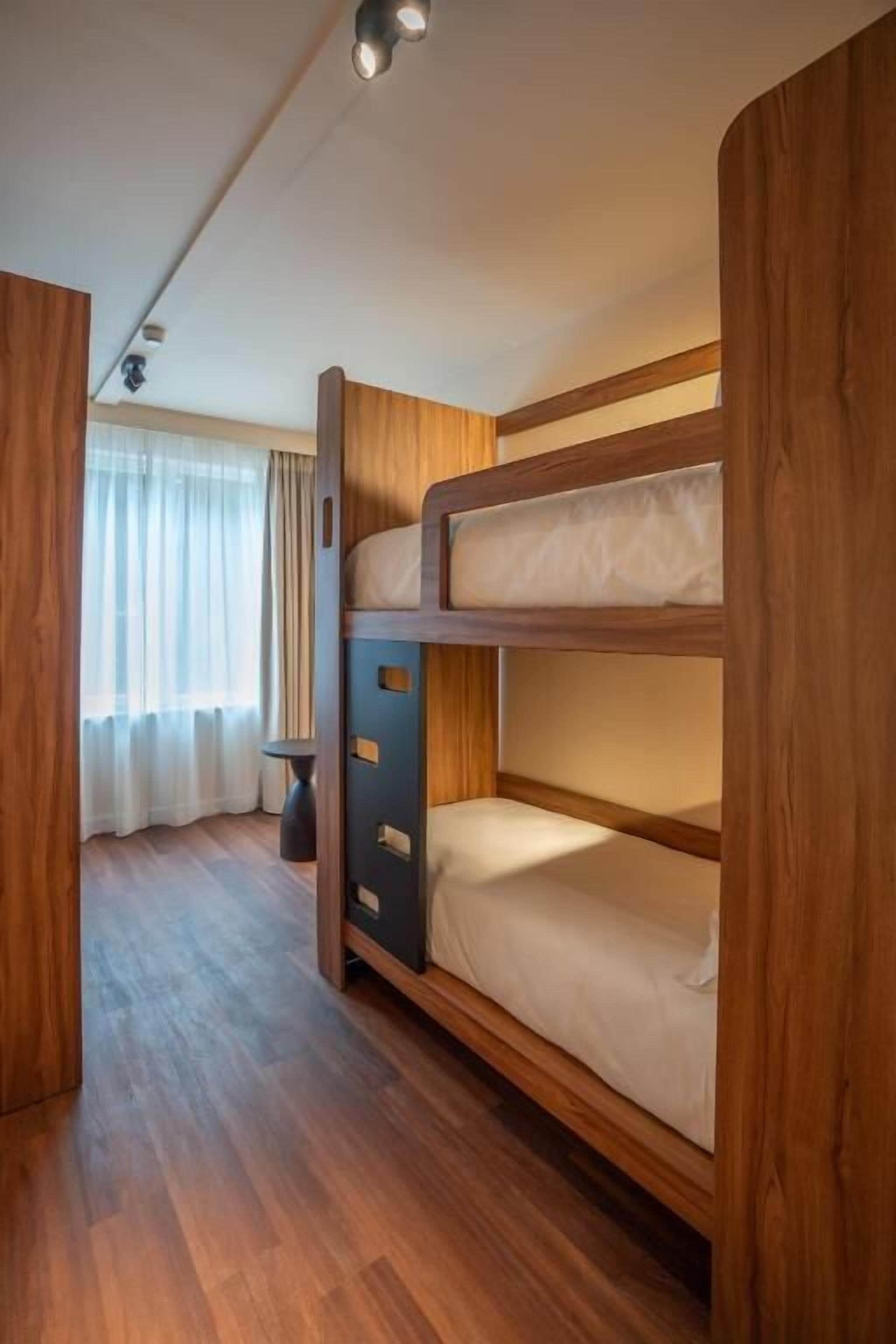Une chambre avec un lit superposé, des murs en bois et une petite table.