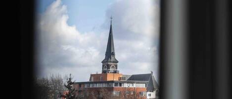 A church with a tall steeple and a clock tower, surrounded by buildings and trees.