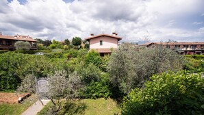 A residential area with a pink house surrounded by lush greenery and other buildings. - Villa Golf in Polpenazze del Garda (Polpenazze del Garda)