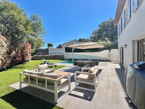 Un giardino con piscina, mobili da esterno e una zona patio coperta.
