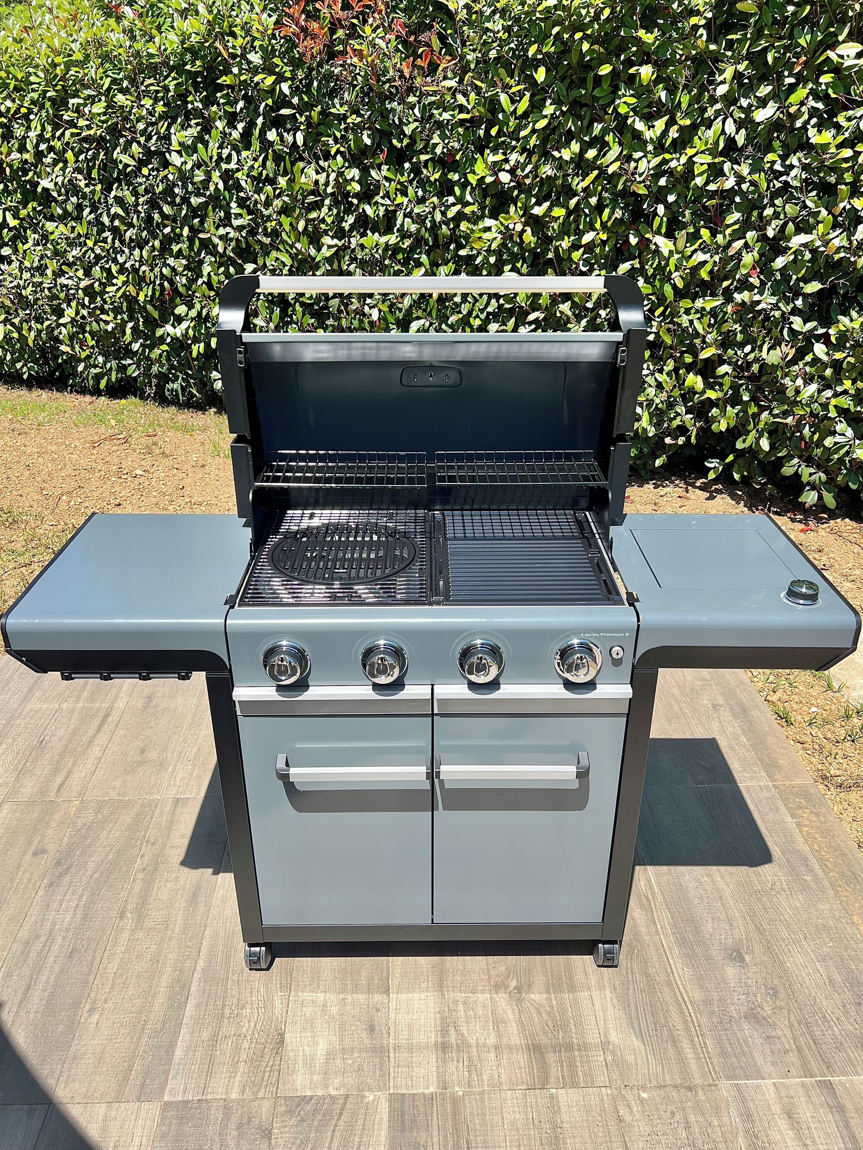 A portable gas grill with a side table, four burners, and a control panel.