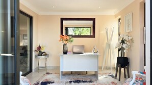 Un espacio de oficina moderno con un escritorio blanco, una computadora portátil ASUS y un florero con flores.