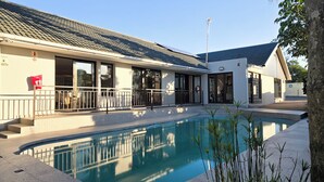 Un edificio con piscina, un patio techado y cielo despejado.