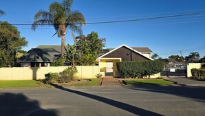 Una casa residencial con jardín delantero, entrada de vehículos y acceso con reja.