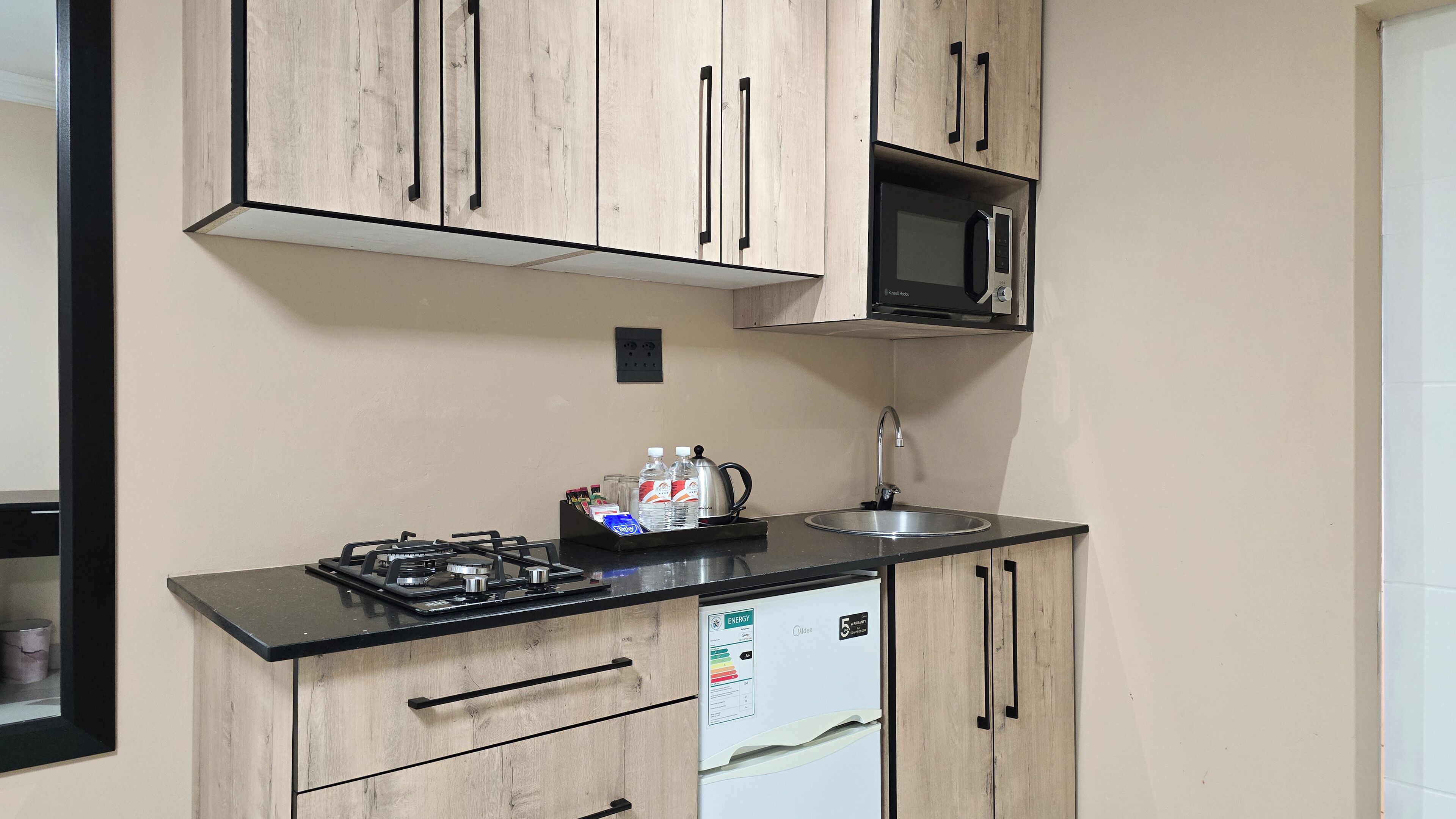A compact kitchen with wooden cabinets, a gas stove, a microwave, and a sink.