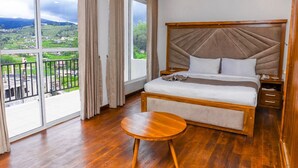 Ein Hotelzimmer mit einem großen Bett, einem kleinen runden Tisch und einem Balkon mit Blick auf die Landschaft.