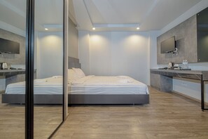 A modern hotel room with a large bed, a desk, a flat-screen TV, and a large mirror. - Karisma95 (Bangkok)