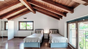 A room with two beds, wooden beams on the ceiling, a window with a view, and a radiator. - Sky Attic Lake Como (Como)