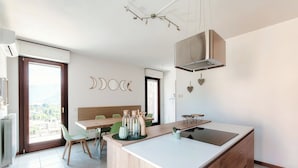 A modern kitchen with a central island, wooden cabinetry, and a view of the outdoors. - Sky Attic Lake Como (Como)