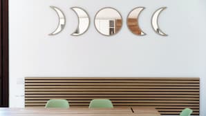 A dining area with a wooden table and green chairs, a wooden slatted bench, and a wall-mounted crescent moon mirror decoration. - Sky Attic Lake Como (Como)