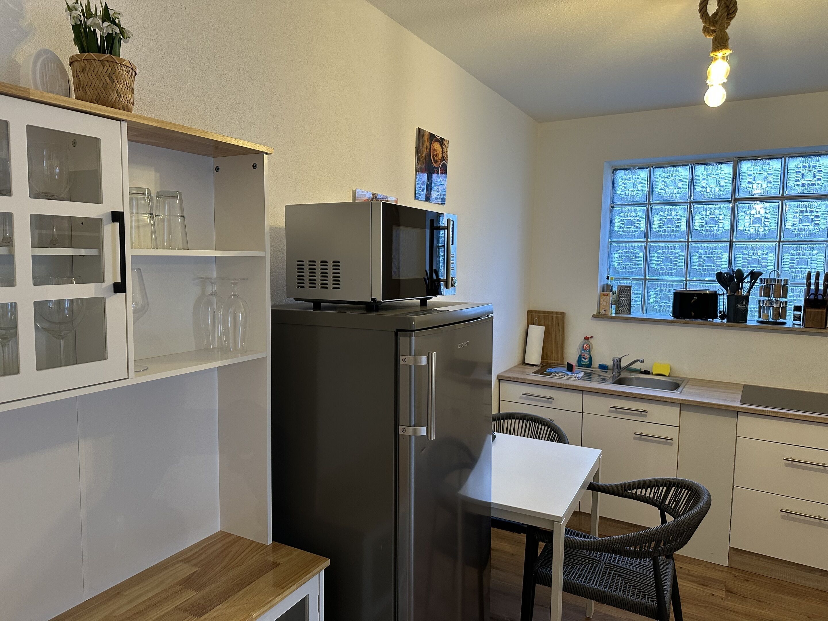 A compact kitchen with a refrigerator, microwave, and a window with a view.