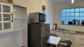 A compact kitchen with a refrigerator, microwave, and a window with a view.