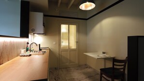 Une cuisine compacte avec un sol en marbre, un comptoir en bois, un évier et une petite table accompagnée d’une chaise.