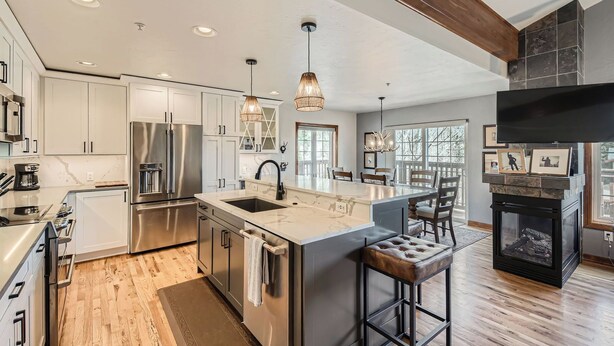 A modern kitchen with stainless steel appliances, a large island, and pendant lighting.