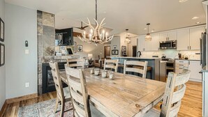 A modern kitchen with a central island, built-in appliances, and a dining area with a wooden table and chairs.