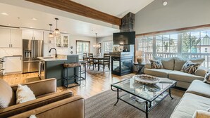 A spacious living area with a large sofa, a glass coffee table, and a fireplace.