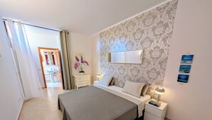 Een keurig opgemaakt slaapkamer met een bed, nachtkastjes, een spiegel en een muur met behang.