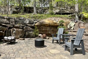 Un patio con sillas Adirondack, una mesa redonda y una chimenea.