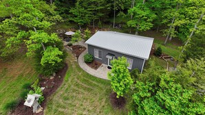 A house surrounded by dense greenery, with a well-maintained lawn and a small patio area.