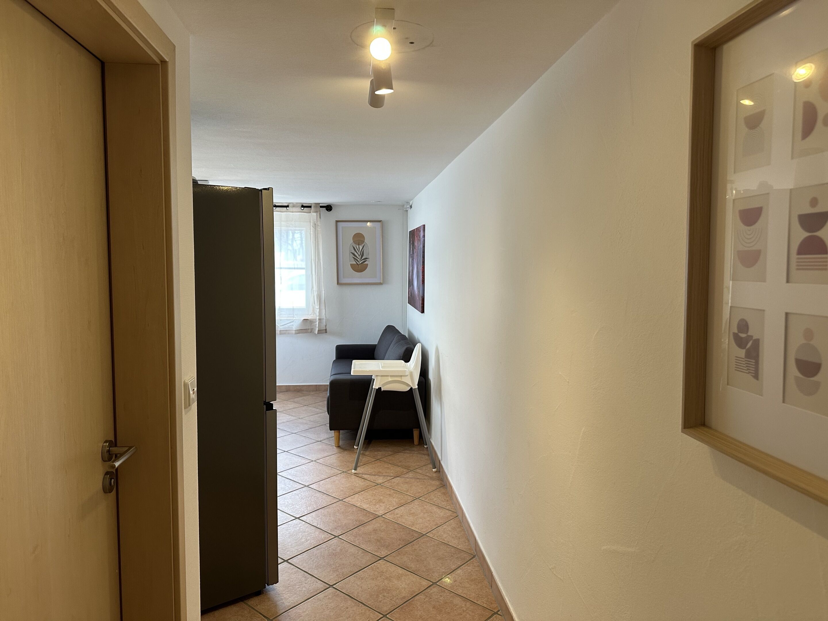 Un couloir avec une porte, un canapé, une chaise et un tableau encadré au mur.